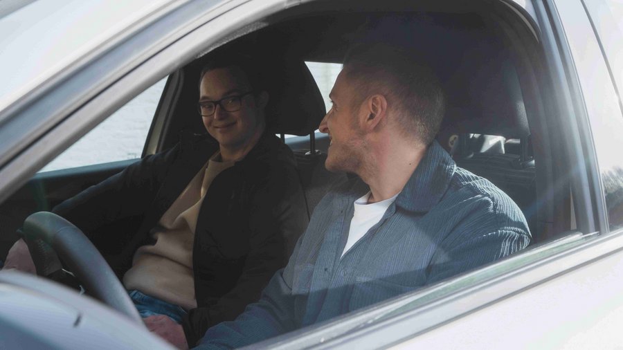 Deux jeunes hommes sont assis dans une voiture et se sourient