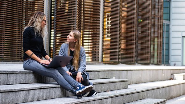 Studentinnen sitzen lachend auf einer Treppe Studentinnen sitzen lachend auf einer Treppe
