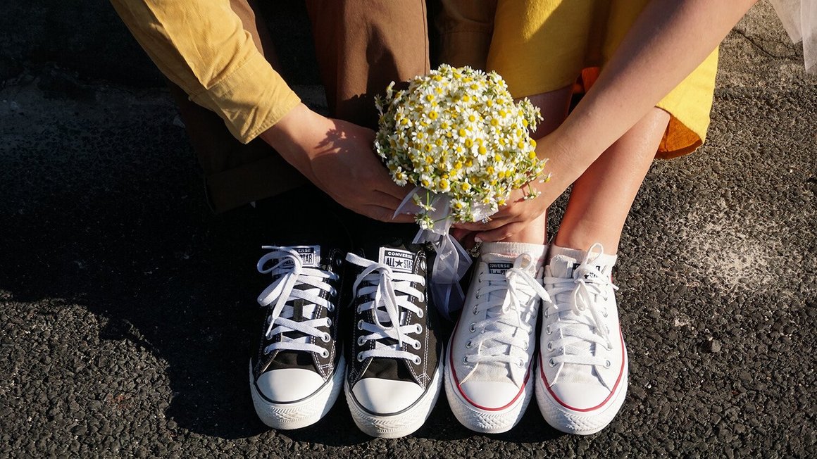 Couple assis par terre, tenant des fleurs dans les mains - Organisation de mariage
