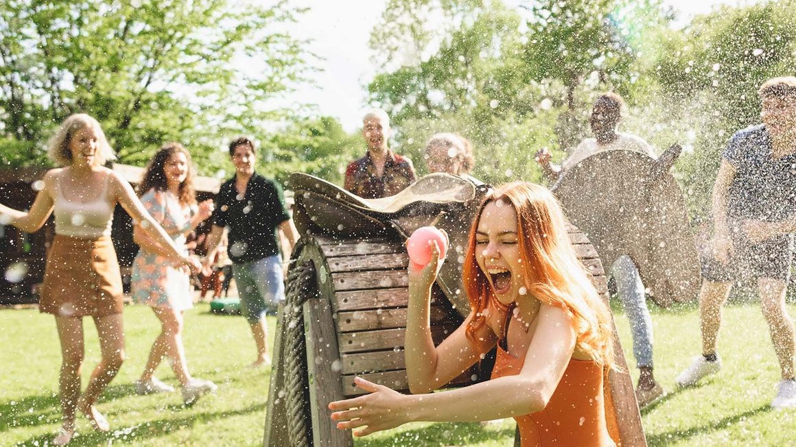 Un groupe de jeunes gens fait une bataille d'eau pendant qu'une femme se cache