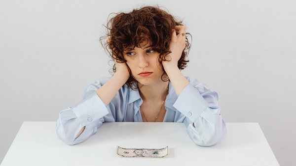 Une femme fait la moue devant un billet de banque – économiser de l‘électricité Une femme fait la moue devant un billet de banque – économiser de l‘électricité
