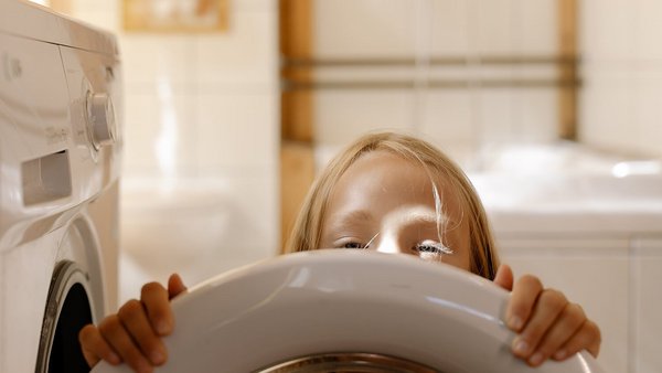 Fille devant une machine à laver - réduire les coûts énergétiques Fille devant une machine à laver - réduire les coûts énergétiques