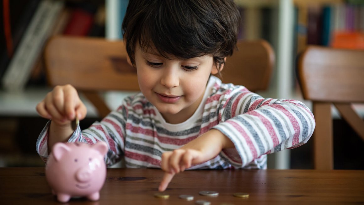 Kind mit Sparschwein und Geldmünzen – Fixkosten 