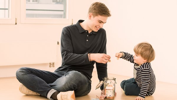 Kind und junger Mann sparen Geld in einem Glas Kind und junger Mann sparen Geld in einem Glas