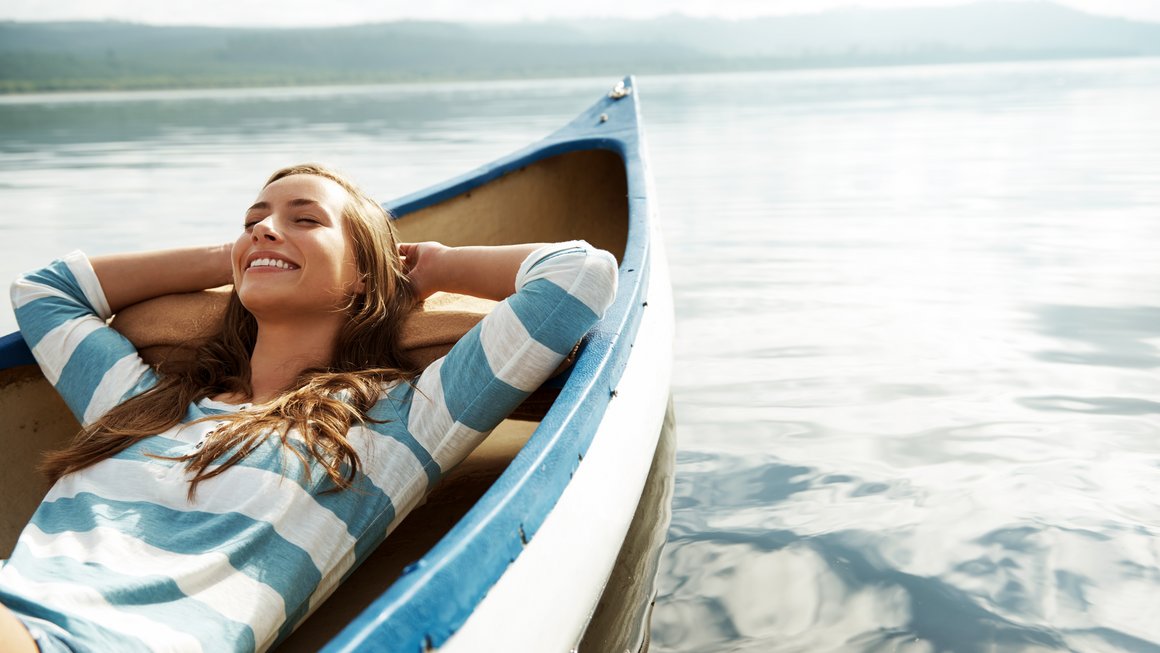 Frau liegt entspannt auf Boot. Trotz Corona entspannt in den Urlaub
