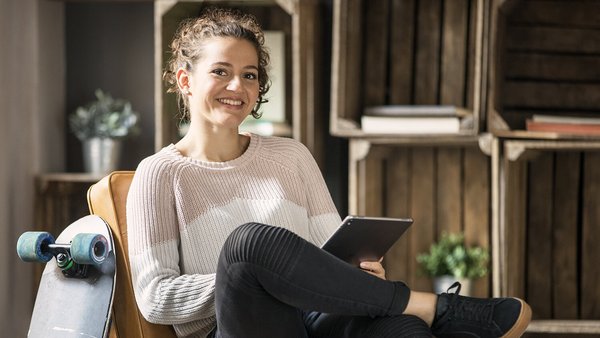 Junge Frau führt Haushaltsbuch am Tablet